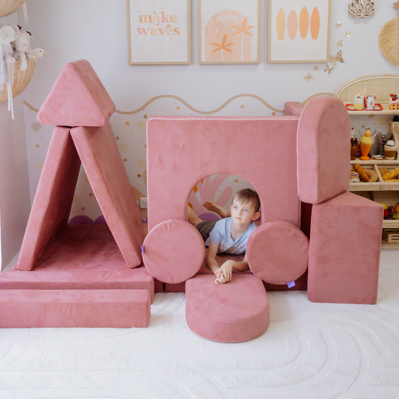 Possum Play Tunnels & Shields in Hibiscus — boy peering through the foam tunnel in an indoor castle fort build